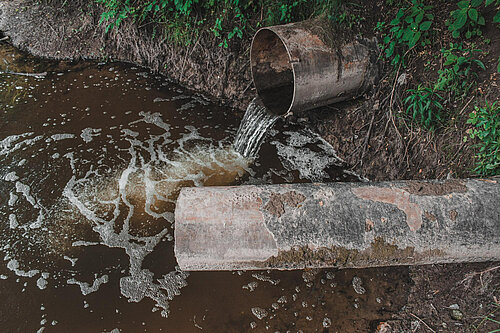 Dirty water pouring from pipe into water course